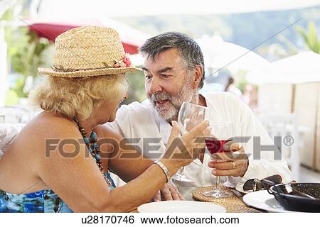 Stock Photograph - Senior Couple Enjoying Meal In Outdoor Restaurant. Fotosearch
