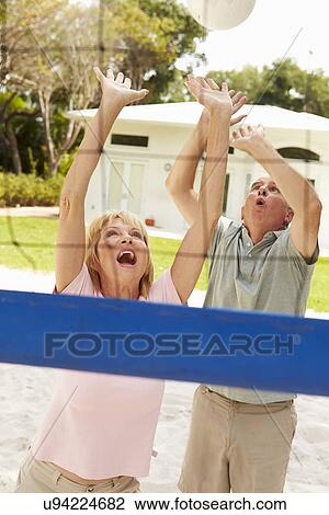 Stock Image - Senior Couple Playing Volleyball Match. Fotosearch