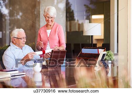Stock Photograph - Senior Couple Putting Will Into Box. Fotosearch