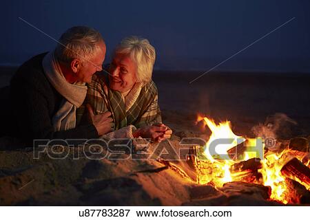 Senior Couple Sitting By Fire On Winter Beach View Large Photo Image Stock Photo - Senior Couple Sitting By Fire On Winter Beach . Fotosearch