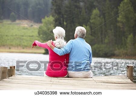 Senior couple sitting on a jetty View Large Photo Image Stock Photo - Senior couple sitting on a jetty. Fotosearch