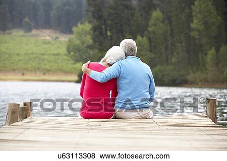 Stock Photo - Senior couple sitting on a jetty. Fotosearch