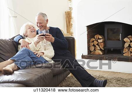 Stock Photo - Senior Couple Sitting On Sofa Drinking Red Wine. Fotosearch