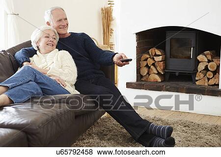 Senior Couple Sitting On Sofa Watching TV View Large Photo Image Stock Photo - Senior Couple Sitting On Sofa Watching TV. Fotosearch
