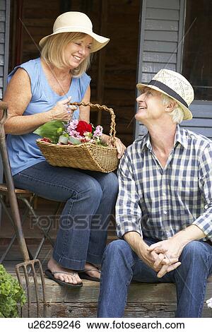 Senior couple sitting on veranda with flowers View Large Photo Image Stock Photograph - Senior couple sitting on veranda with flowers. Fotosearch