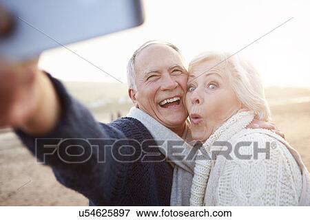 Senior Couple Standing On Beach Taking Selfie View Large Photo Image Stock Photo - Senior Couple Standing On Beach Taking Selfie. Fotosearch