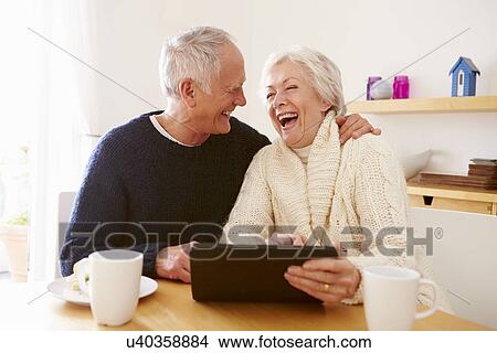 Senior Couple Using Digital Tablet At Table View Large Photo Image Picture - Senior Couple Using Digital Tablet At Table. Fotosearch