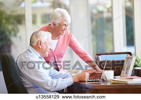 Senior Couple Using Laptop On Desk At Home View Large Photo Image Stock Photo - Senior Couple Using Laptop On Desk At Home. Fotosearch