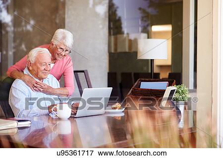 Senior Couple Using Laptop On Desk At Home View Large Photo Image Stock Photo - Senior Couple Using Laptop On Desk At Home. Fotosearch