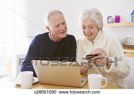 Stock Image - Senior Couple Using Laptop To Shop Online. Fotosearch