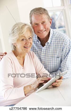 Senior couple using tablet at home View Large Photo Image Stock Photograph - Senior couple using tablet at home. Fotosearch