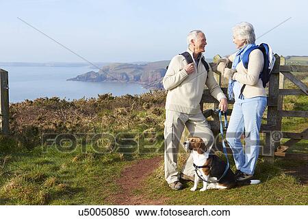 Stock Image - Senior Couple Walking Along Coastal Path. Fotosearch