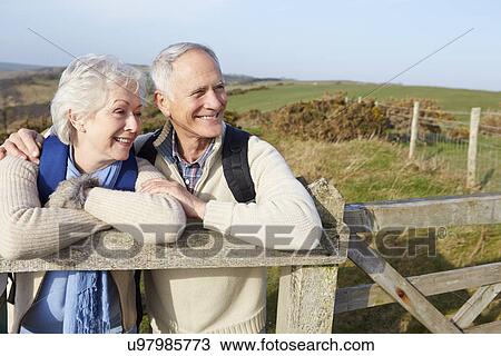 Stock Image - Senior Couple Walking Along Coastal Path. Fotosearch
