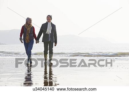 Senior Couple Walking Along Winter Beach View Large Photo Image Stock Image - Senior Couple Walking Along Winter Beach. Fotosearch