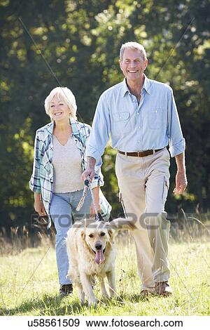 Stock Photo - Senior couple walking dog. Fotosearch