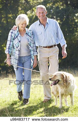 Stock Photo - Senior couple walking dog. Fotosearch