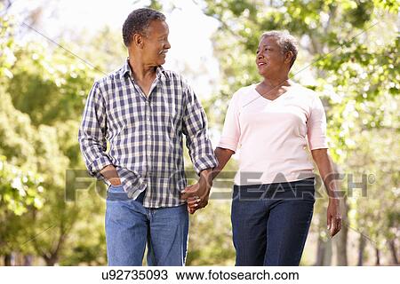 Stock Image - Senior couple walking in park. Fotosearch