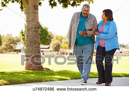 Stock Photograph - Senior Couple Walking In Park Together. Fotosearch