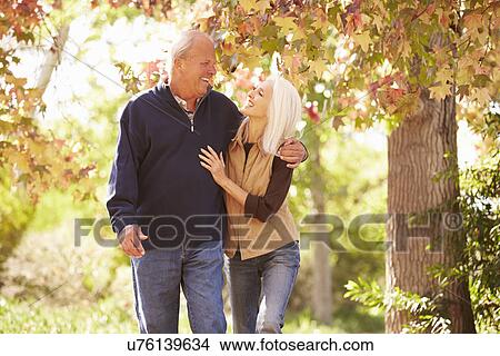 Picture - Senior Couple Walking Through Autumn Woodland. Fotosearch