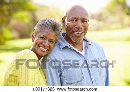 Stock Image - Senior Couple Walking Through Autumn Woodland. Fotosearch