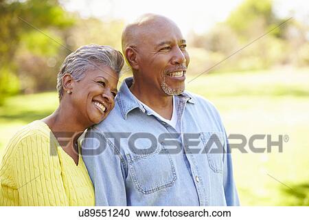 Stock Image - Senior Couple Walking Through Autumn Woodland. Fotosearch