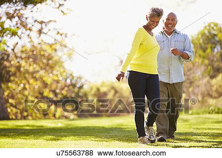 Stock Photo - Senior Couple Walking Through Autumn Woodland. Fotosearch