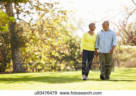Stock Photo - Senior Couple Walking Through Autumn Woodland. Fotosearch