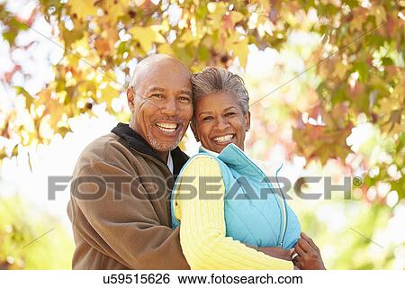 Stock Photograph - Senior Couple Walking Through Autumn Woodland. Fotosearch