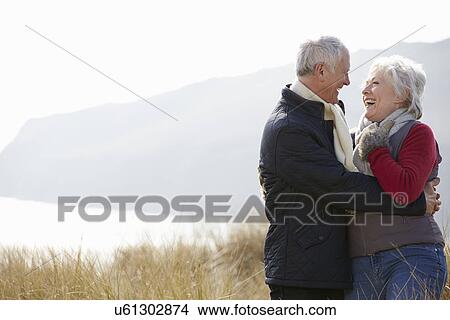 Senior Couple Walking Through Sand Dunes On Winter Beach View Large Photo Image Picture - Senior Couple Walking Through Sand Dunes On Winter Beach. Fotosearch