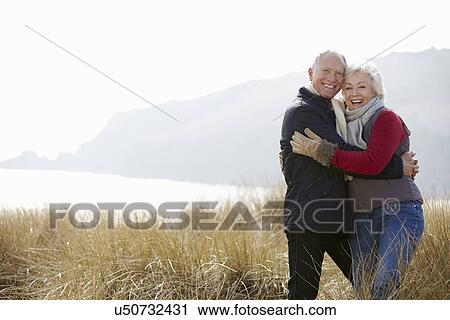 Senior Couple Walking Through Sand Dunes On Winter Beach View Large Photo Image Stock Image - Senior Couple Walking Through Sand Dunes On Winter Beach. Fotosearch