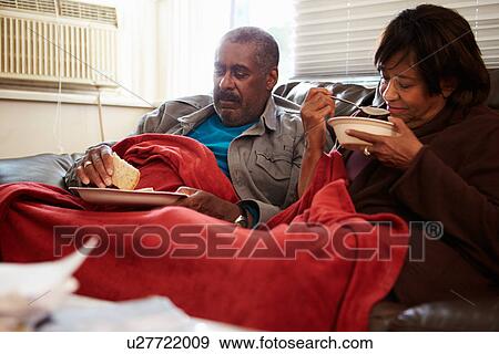 Stock Photo - Senior Couple With Poor Diet Keeping Warm Under Blanket . Fotosearch
