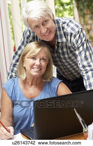 Stock Image - Senior Couple Working In Home Office. Fotosearch