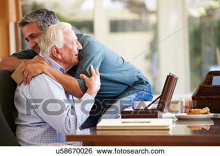 Stock Photograph - Senior Father Being Comforted By Adult Son. Fotosearch