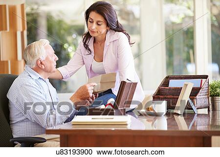Stock Image - Senior Father Discussing Document With Adult Daughter. Fotosearch