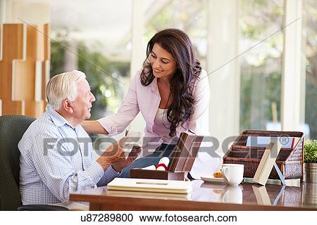 Stock Image - Senior Father Discussing Document With Adult Daughter. Fotosearch