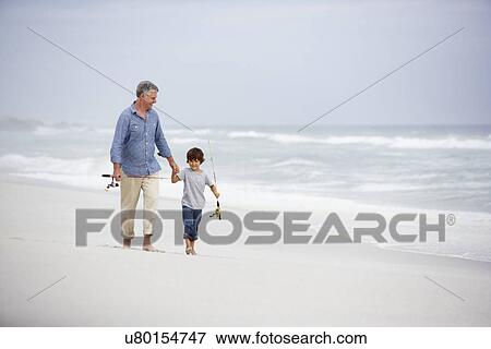 Stock Photo - Senior man and grandson walking on beach. Fotosearch