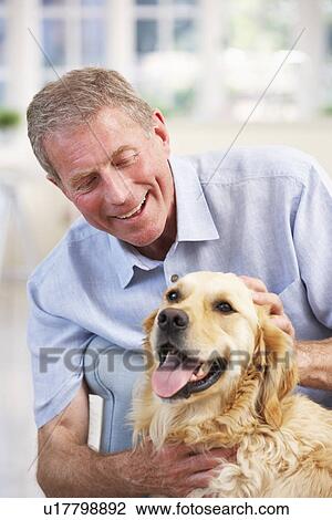 Stock Image - Senior man at home with dog. Fotosearch