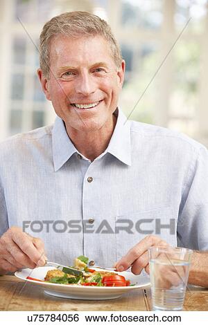 Senior man eating meal at home View Large Photo Image Stock Photograph - Senior man eating meal at home. Fotosearch