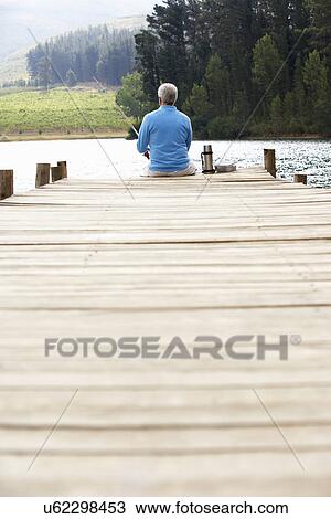 Stock Image - Senior man fishing on jetty. Fotosearch