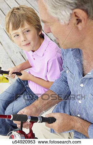 Stock Image - Senior man fishing with grandson. Fotosearch
