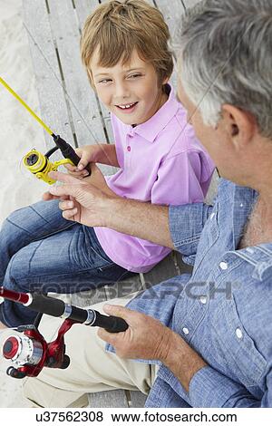 Stock Photo - Senior man fishing with grandson. Fotosearch