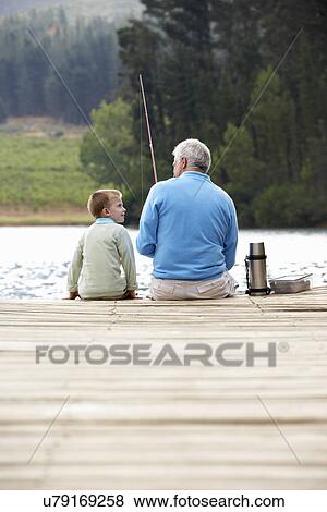 Stock Photo - Senior man fishing with grandson. Fotosearch