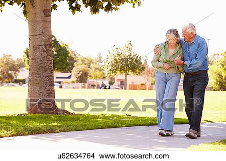 Picture - Senior Man Helping Wife As They Walk In Park Together. Fotosearch
