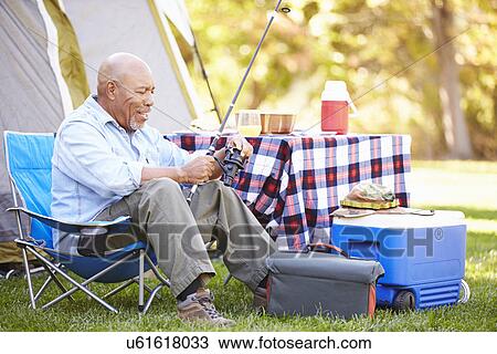 Stock Image - Senior Man On Camping Holiday With Fishing Rod. Fotosearch