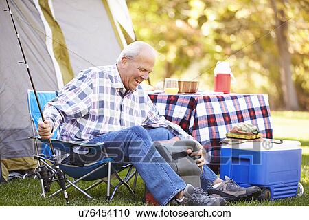 Stock Image - Senior Man On Camping Holiday With Fishing Rod. Fotosearch