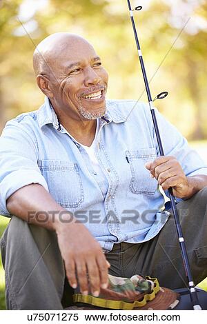 Stock Photography - Senior Man On Camping Holiday With Fishing Rod. Fotosearch