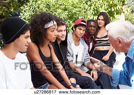 Stock Photo - Senior Man Talking With Gang Of Young People. Fotosearch