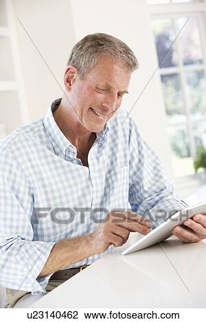 Senior man using tablet at home View Large Photo Image Stock Image - Senior man using tablet at home. Fotosearch