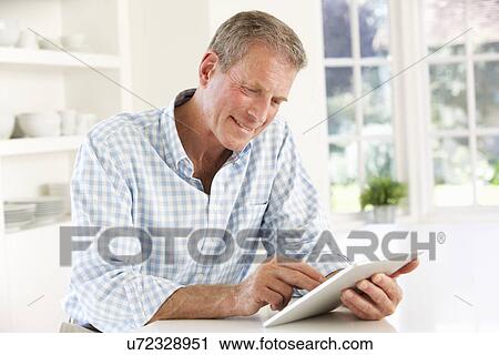 Senior man using tablet at home View Large Photo Image Stock Image - Senior man using tablet at home. Fotosearch