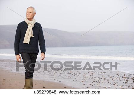 Stock Photo - Senior Man Walking Along Winter Beach. Fotosearch